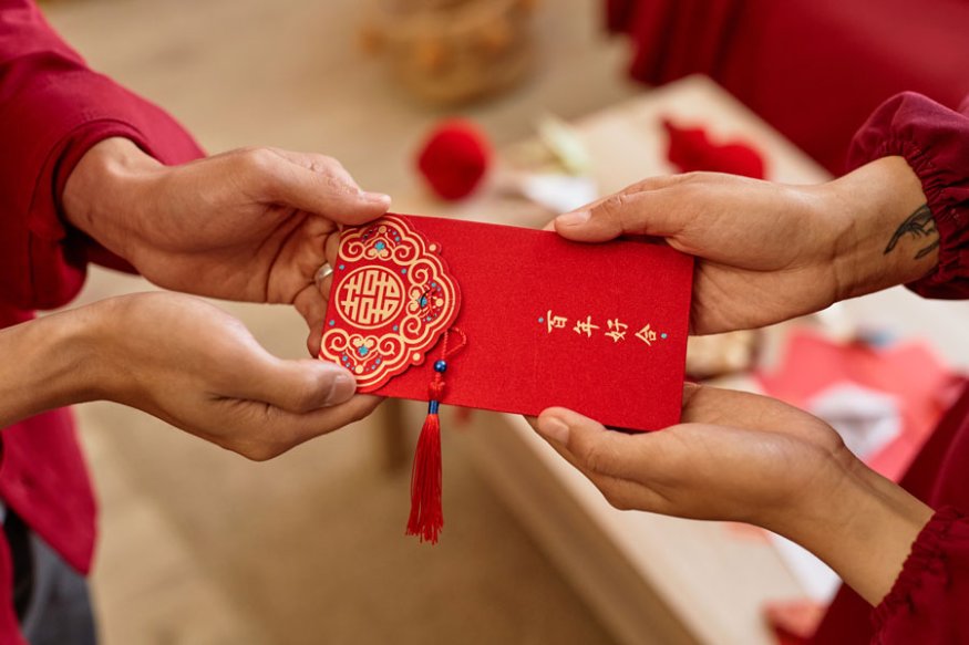 Newlyweds receiving a red ang bao packet from a guest during a Singapore wedding banquet